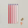 Set of red and pink pencils with a sharpener on a gray background