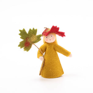 Felted doll with a yellow dress and red hat holding a leaf on a white background