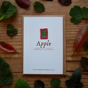 Card with 'Apple' design surrounded by leaves on a wooden surface