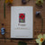 Card with a poppy design surrounded by flowers on a wooden surface