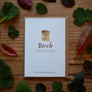 Card with 'Birch' design surrounded by leaves on a wooden surface