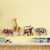 Colorful animal-shaped hooks on a yellow wall above a shelf with toys.