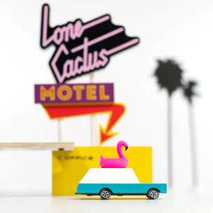 Candylab wooden toy wagon with a pink flamingo on the roof in front of a motel | Conscious Craft