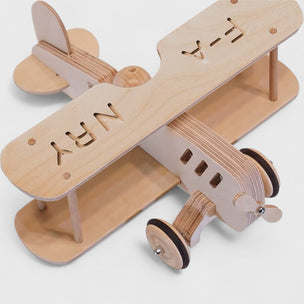 Wooden toy airplane with cut-out letters on a light gray background