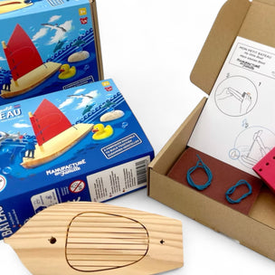 Wooden toy boat, packaging, and cardboard box on a white background
