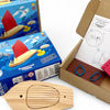 Wooden toy boat, packaging, and cardboard box on a white background