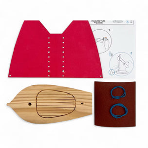 Wooden toy boat kit with red sail, wooden boat, and instruction sheet on a white background