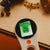 Handheld device with a digital display on a wooden surface with natural objects.