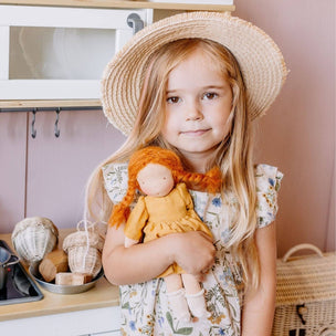 Young girl holding a doll in a kitchen setting
