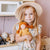 Young girl holding a doll in a kitchen setting