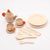 Wooden toy tea set with teapot, cups, saucers, and utensils on a white background