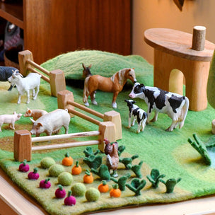 Model farm scene with animals and plants on a green felt background