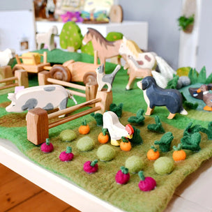 Toy farm set with animals and vegetables on a green felt surface