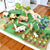Wooden farm animals and structures on a green felt play mat.