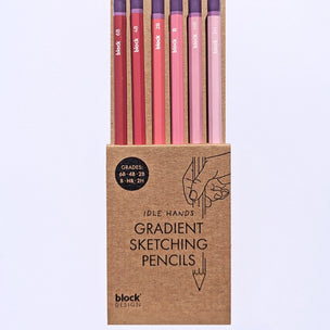 Set of gradient sketching pencils in a cardboard box on a light purple background