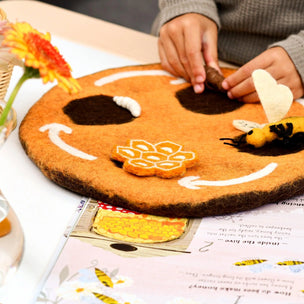 Children's play mat with bee and flower design on a table