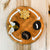 Round felt board with embroidered bee, flower, and honeycomb on a wooden surface