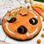 Round orange felt board with bee and honeycomb decorations on a white surface.