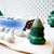Felted green tree and white balls on a textured surface with a blurred background