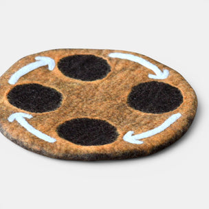 Round brown mat with black circles and white arrows on a light gray background