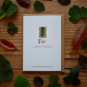 Card with 'Fir' design surrounded by leaves on a wooden surface