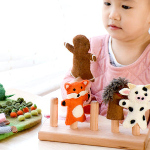 Child playing with a wooden toy featuring animal figures on a white background