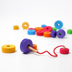 Grimms First Thread Game has a wooden threader on a string and various wooden rings in bright colours to thread | Conscious Craft