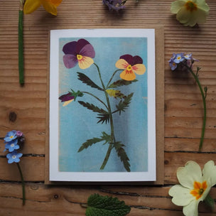 Floral card with pressed flowers on a wooden surface