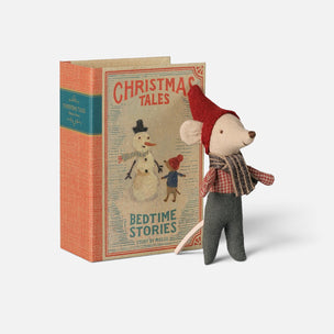 A small Maileg mouse figurine wearing a red hat and striped scarf stands beside a vintage-style hardcover book titled "Christmas Tales: Bedtime Stories" on a light gray background.