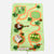 A felted wool activity rug shaped like a golf course map, featuring green grassy areas, orange winding paths, clover shapes, a small flag, a basket, a golf ball, and a putt-putty, on a light gray background.