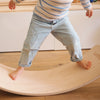 Child walking on a wooden Wobbel balance board indoors