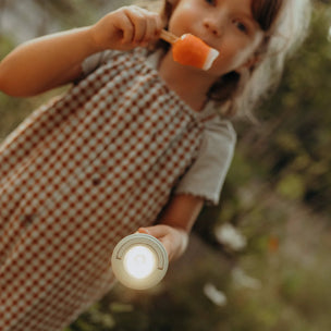 Child holding a glowing lantern and an orange object outdoors