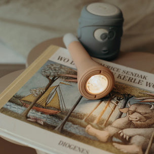 Small flashlight on a book with a cup in the background