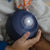 Hand holding a blue night light on a bed