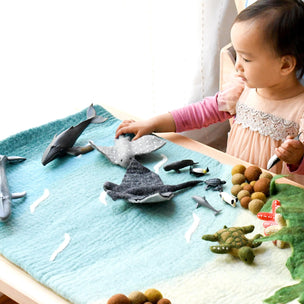 Child playing with toy sea creatures on a felt play mat