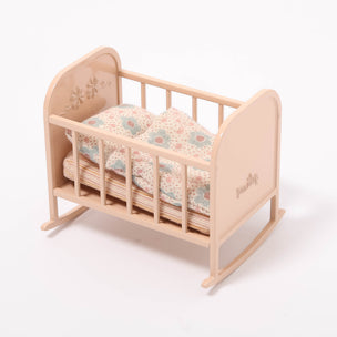 Wooden baby crib with floral bedding on a white background