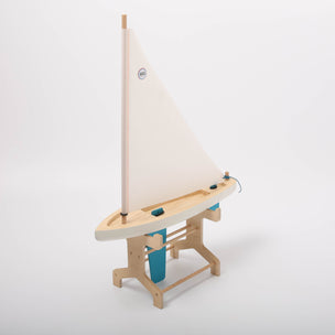Wooden toy sailboat with a white sail on a light gray background