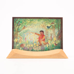 Postcard with a colorful illustration of a child in a garden, surrounded by animals and flowers, on a white background.