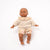 Baby doll wearing a beige outfit with a ruffled collar and floral shorts on a white background