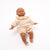 Baby doll wearing a beige sweater and floral shorts on a white background