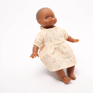 Doll wearing a beige dress with a subtle pattern on a white background