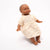 Doll wearing a beige dress with a subtle pattern on a white background