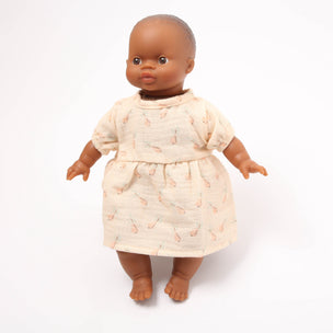 Doll wearing a cream dress with a subtle pattern on a white background