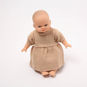 Baby doll wearing a beige dress on a white background