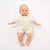 Baby doll wearing a cream outfit on a white background