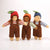 Three dolls wearing brown overalls and colorful hats on a white background