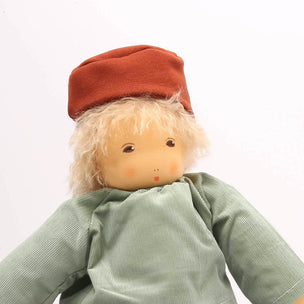 Toy figure with a red hat and green shirt standing on a wooden arch against a white background