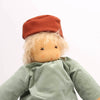 Toy figure with a red hat and green shirt standing on a wooden arch against a white background