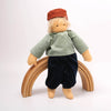 Toy figure with a green shirt and black pants standing on a wooden arch against a white background