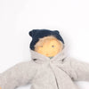 Doll wearing a gray jacket, brown pants, and blue hat on a white background